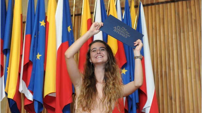 TFAS Prague student celebrates at graduation after receiving diploma.